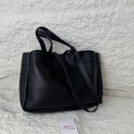 Elegant black tote bag on textured surface with tag.