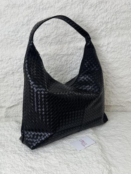 Elegant woven black hobo bag for women on textured background.
