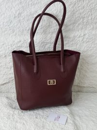 Burgundy leather tote bag from Daisy Store on textured background.