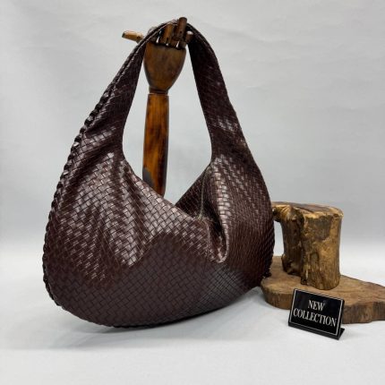 Woven brown handbag on display with 'New Collection' sign.