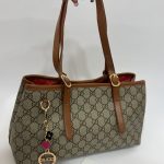 Gucci GG monogram handbag with red lining and brown leather handles.
