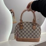 Louis Vuitton Alma BB handbag with checkered pattern and leather accents.