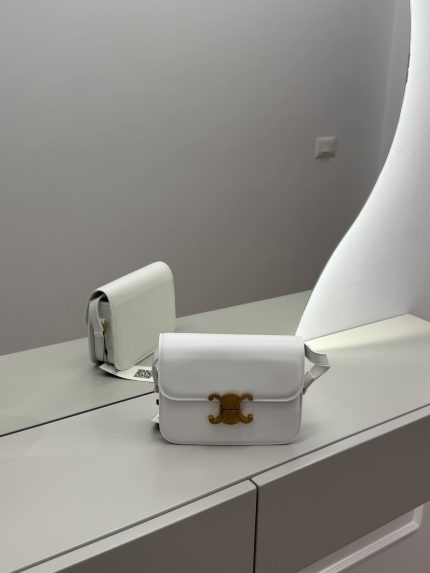 White Celine mini bag on mirrored surface, elegant and stylish design.