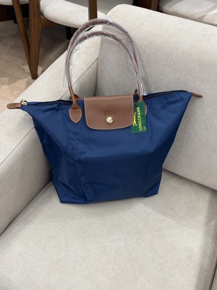 Blue Longchamp Le Pliage XL bag on beige sofa.