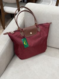 Longchamp Le Pliage XL tote bag in burgundy on sofa.