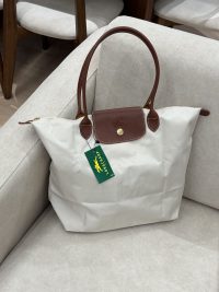 White Longchamp Le Pliage XL bag with brown leather handles.