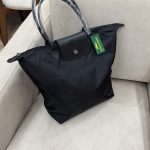 Black Longchamp Le Pliage XL bag on beige sofa.