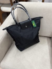 Black Longchamp Le Pliage XL bag on beige sofa.