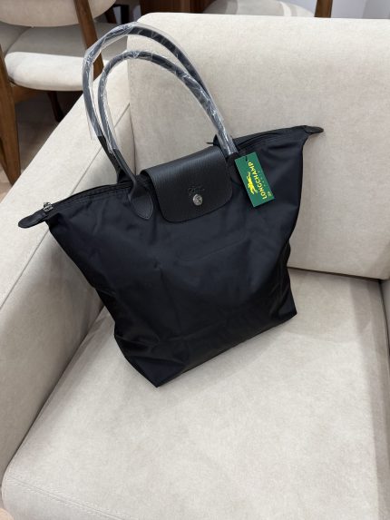 Black Longchamp Le Pliage XL bag on beige sofa.