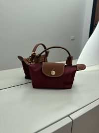 Çanta Femrash Longchamp Le Pliage XS burgundy handbag on table.
