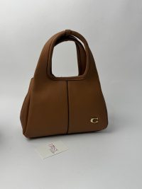 Brown Coach tote bag with gold C logo on white background.