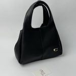 Black Coach Tote Bag with gold C logo on display.