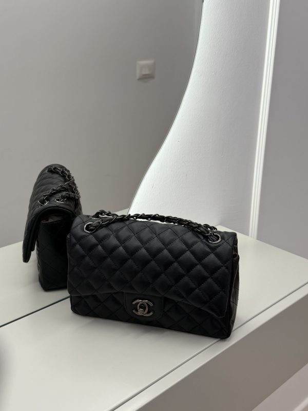 Elegant black Chanel Classic Flap bag on mirrored surface.