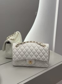 White Chanel Classic Flap bag with gold chain on mirrored surface.