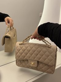 Beige Chanel Classic Flap bag with gold chain handle reflection.