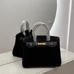 Luxurious black Hermes Birkin Bag on mirrored surface.
