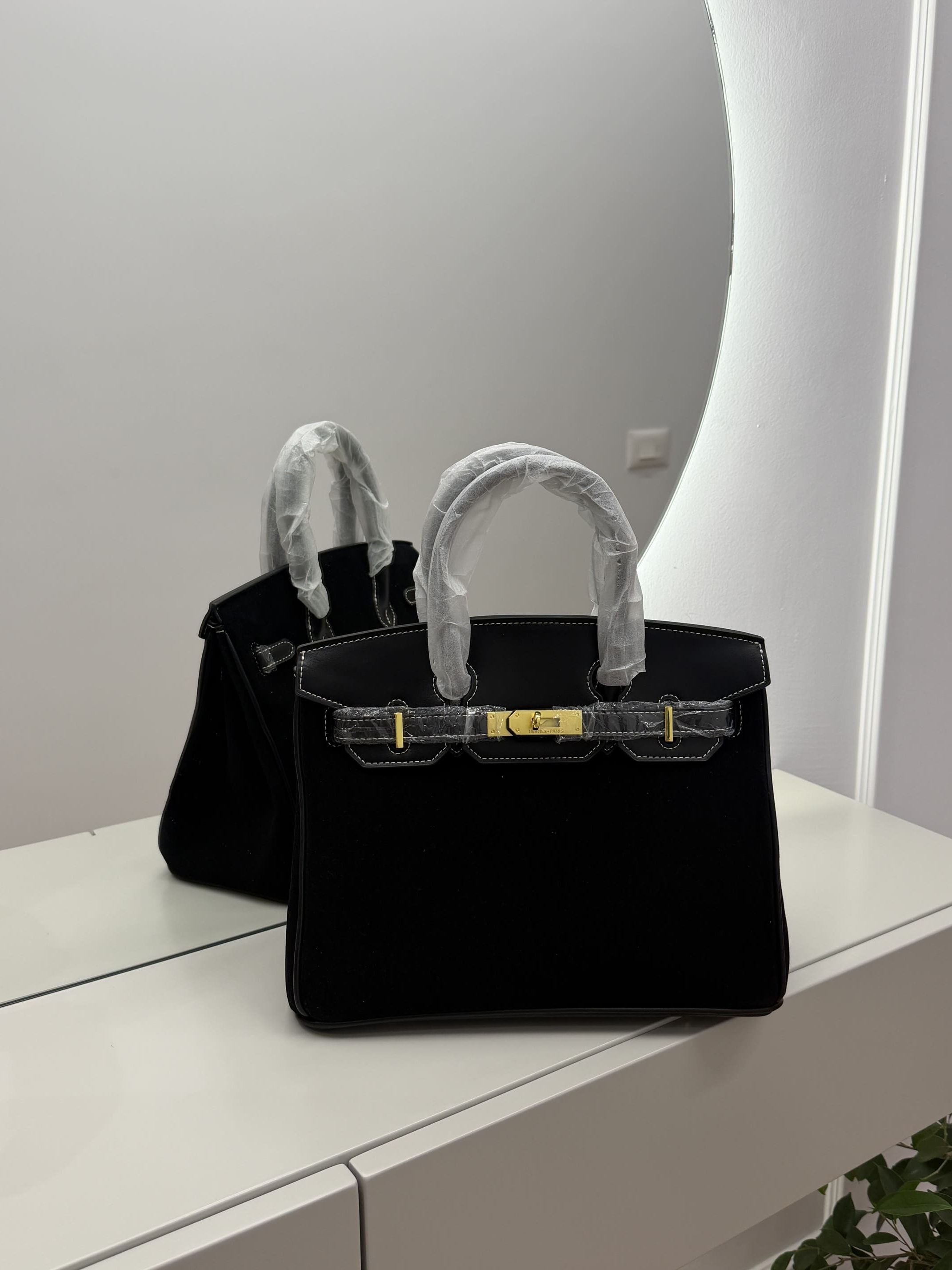 ds-canta-187-kryesore Luxurious black Hermes Birkin Bag on mirrored surface.