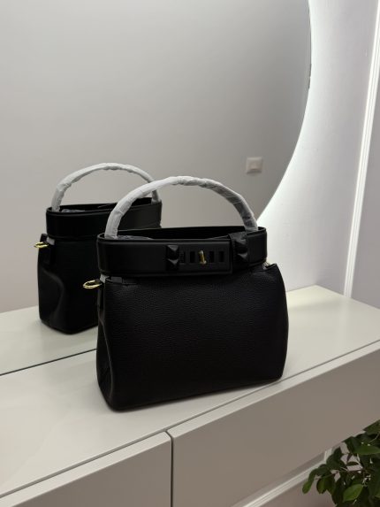 Çanta bucket with studded strap on mirrored surface.