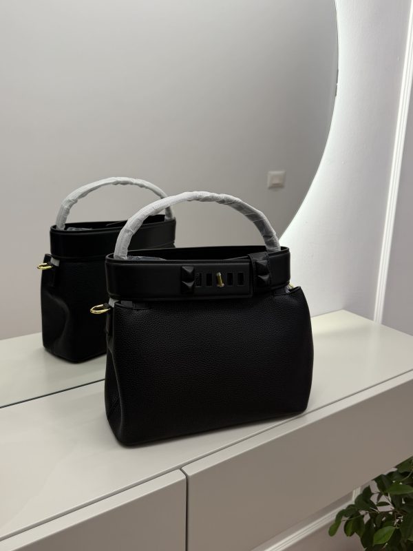 Çanta bucket with studded strap on mirrored surface.