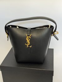 Elegant YSL black bucket bag with gold logo detail on box.