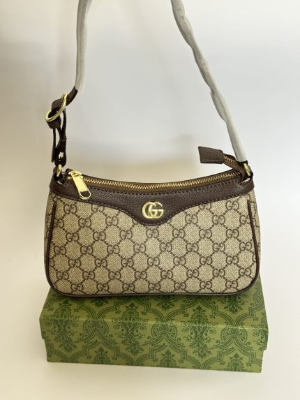Canta Gucci Ophidia GG handbag on decorative box, elegant luxury fashion.