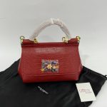 Red Dolce Gabbana Sicily handbag with jeweled accent on black cloth.
