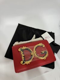 Red Dolce Gabbana bag with gold DG logo on black cloth.