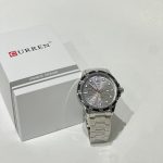 Curren Ora Diver watch with silver bracelet and box on white background.