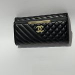 Black Chanel women's wallet with quilted design and logo.
