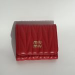 Red quilted women's wallet with gold logo on white background.