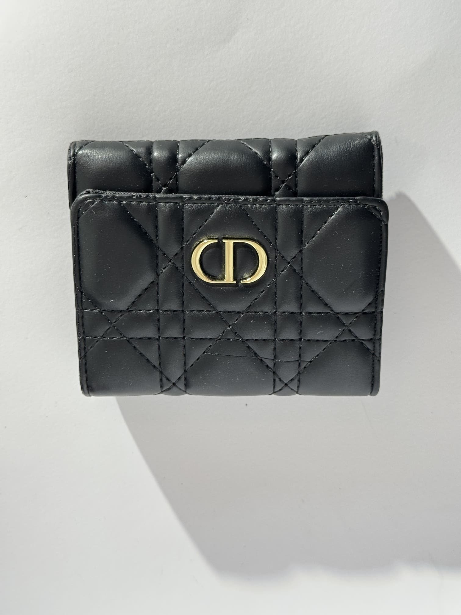 ds-portofola-043-kryesore Black quilted women's wallet with gold emblem, elegant and stylish.