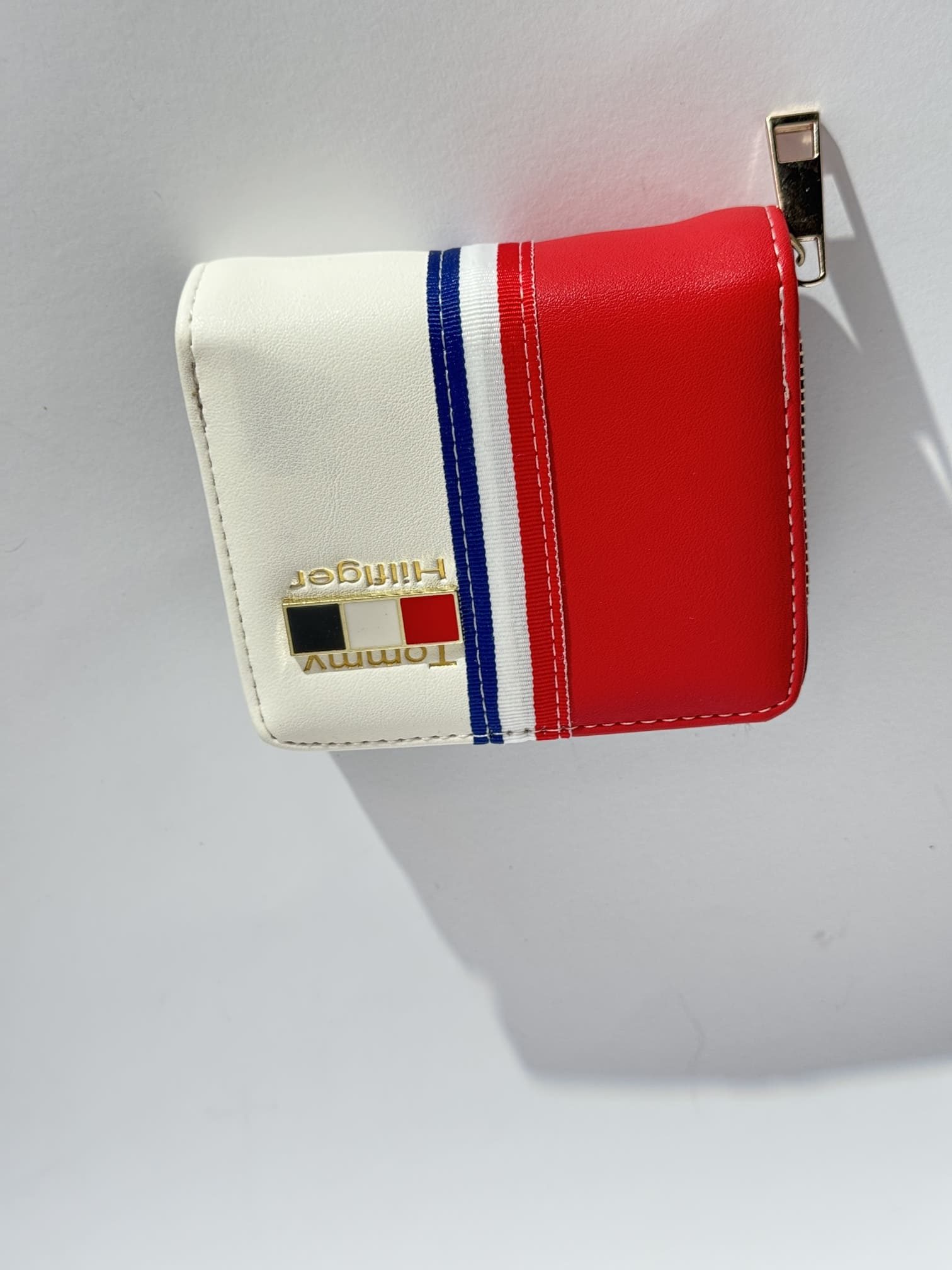 ds-portofola-044-kryesore Red, white, blue wallet with gold logo, elegant design.