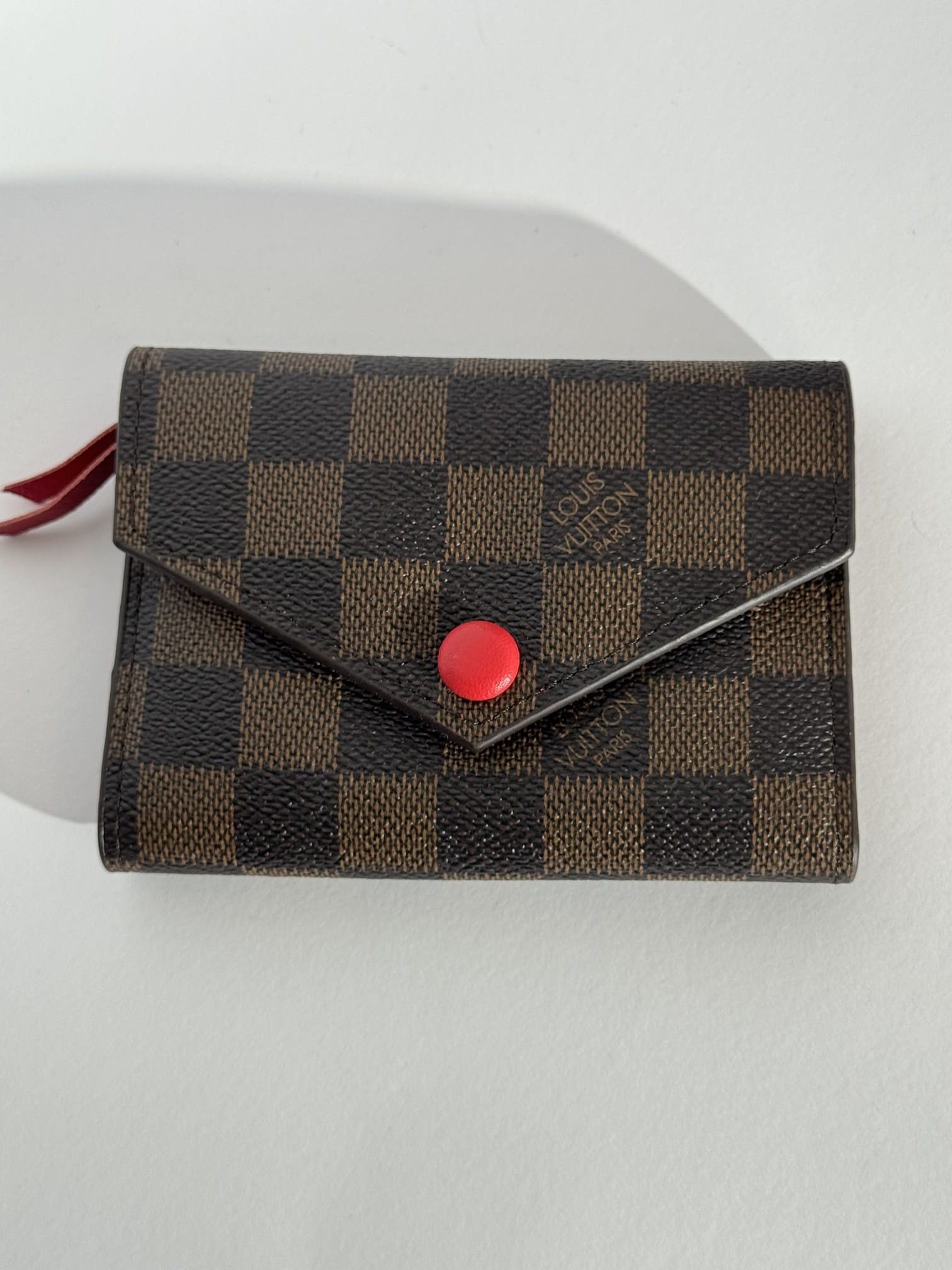 ds-portofola-048-kryesore Checkered Goyard wallet with red button, elegant style.