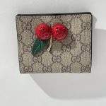 Gucci Portofol Femrash wallet with cherry embellishment on monogram canvas.