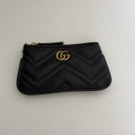 Black Gucci Marmont zip pouch with gold logo detail.