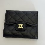Black quilted Chanel wallet with gold logo on white background.