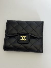 Black quilted Chanel wallet with gold logo on white background.