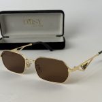 Miu Miu women's sunglasses with gold frame and brown lenses.