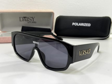 Black Versace sunglasses with branded cases in background.
