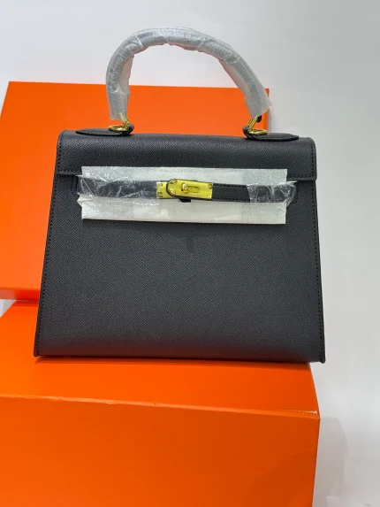 Çantë moderne HERMES KELLY 25 për femra, ngjyrë e zezë, mbi kuti portokalli.
