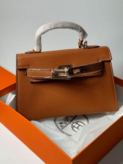 Hermes Kelly brown leather handbag in orange box, ideal for women.