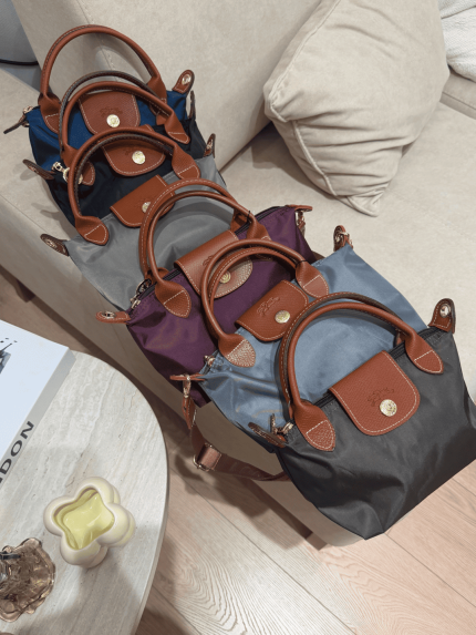 Colorful Longchamp Le Pliage Small bags on sofa display.