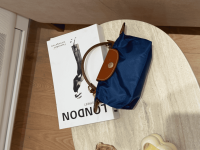 Blue Longchamp Le Pliage XS bag on table, elegant and compact.