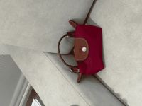 Red Longchamp Le Pliage XS handbag on gray surface.