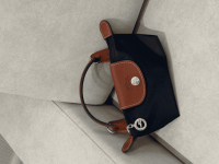 Çanta femrash Longchamp Le Pliage XS, elegante dhe komode, në kanape.