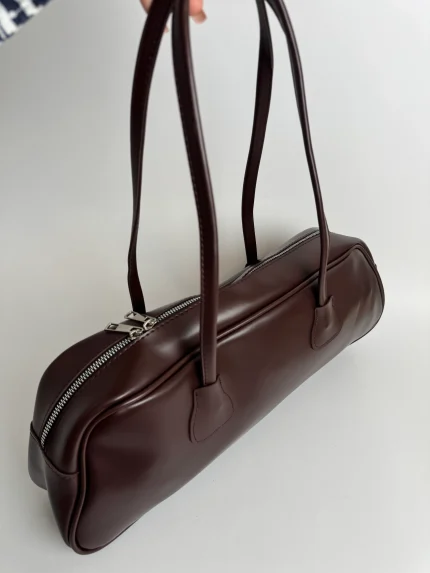 Elegant brown women's handbag with long handles and zipper closure.
