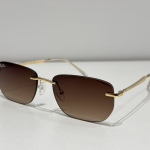 Syze dielli Ray-Ban me kornizë të artë dhe lente kafe për stil dhe mbrojtje.
