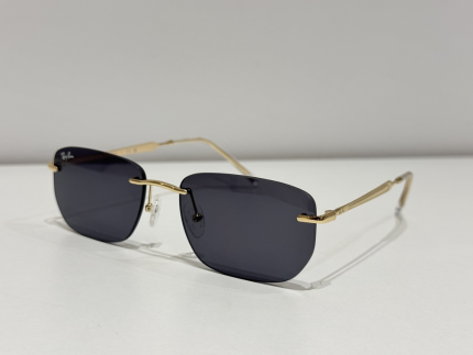 Syze dielli Ray-Ban me kuadrin e artë dhe lentet e errëta.