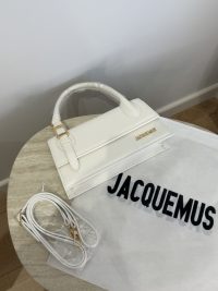 White Jacquemus Le Chiquito Long handbag on table with strap and dust bag.