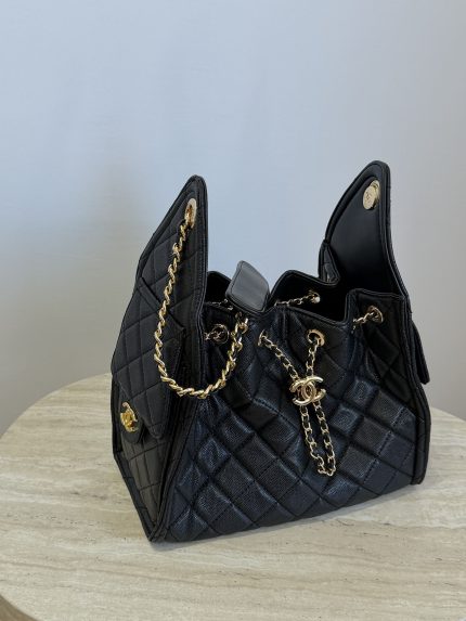 Elegant black Chanel bag with gold chain accents on table.